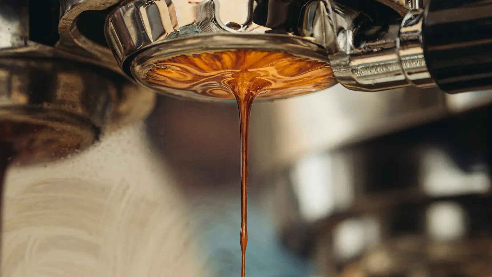 Espresso dripping from a portafilter into a yellow cup